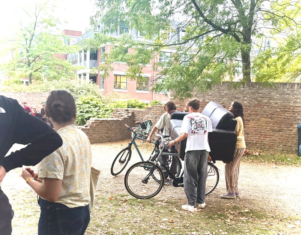 自転車必須：ムービーナイトに向けて、自転車でソファを運ぶ学生たち